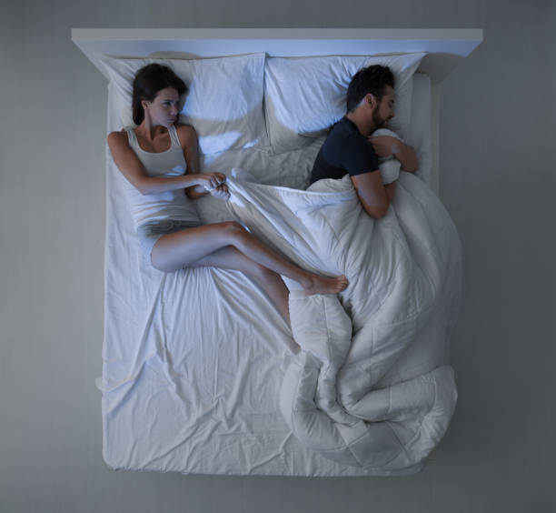 Sheets stealing Couple sleeping in bed, the man is stealing the duvet and the woman is angry and freezing man sleeping top view stock pictures, royalty-free photos & images