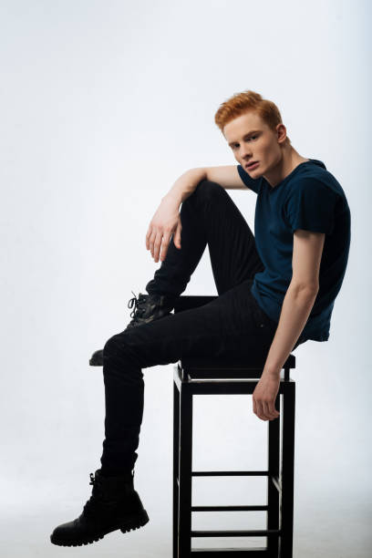 istock Concentrated red-headed young man sitting on the chair 906734132