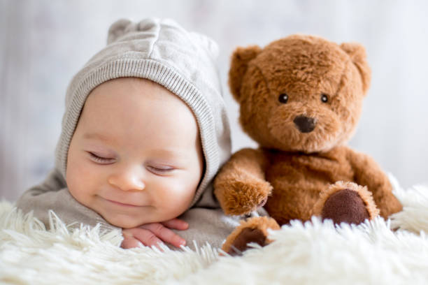 istock Sweet baby boy in bear overall, sleeping in bed with teddy bear 906734962