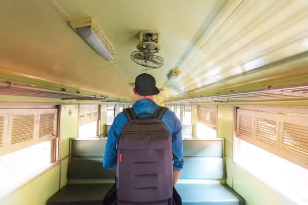 Man with backpack walking in a wagon of a old vintage train. Travel backpacker concept