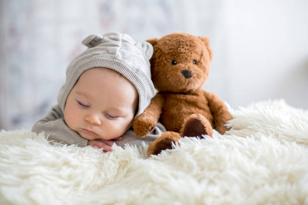 istock Sweet baby boy in bear overall, sleeping in bed with teddy bear 906740040