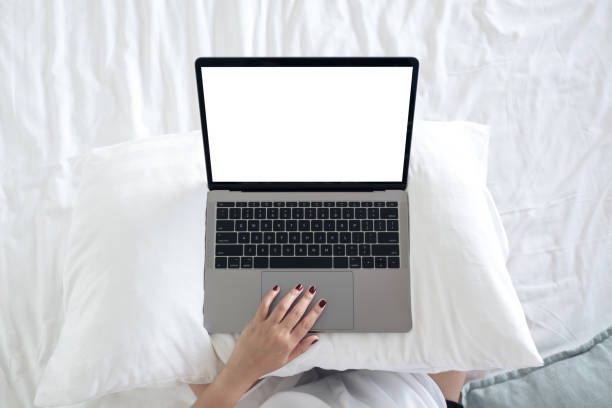 istock Top view mockup image of a woman sitting on a bed , using and touching on laptop with blank white desktop screen  keyboard 906740066