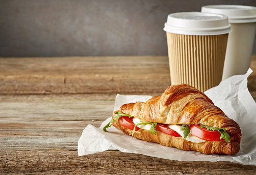 croissant sandwich with tomato and mozzarella on wooden table