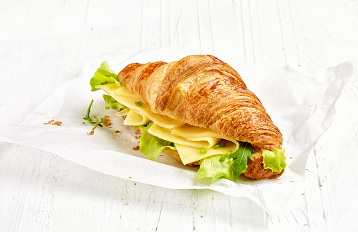 croissant sandwich with cheese on white wooden table