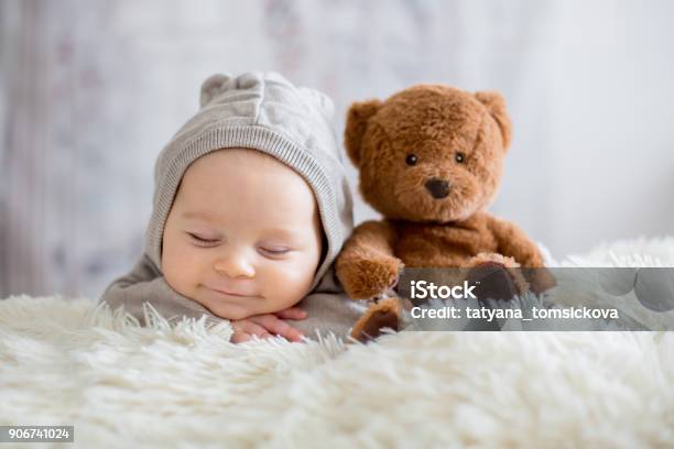 Sweet Baby Boy In Bear Overall Sleeping In Bed With Teddy Bear Stock Photo - Download Image Now