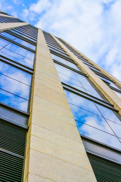 istock Looking up at skyscrapers with glass windows under blue sky and white clouds 906743574