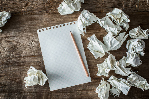 istock White square paper, pencil and wasted papers on wooden back ground 906752592