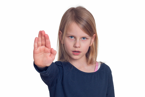 Portrait of a Caucasian girl, the child holds omega-3 gelatin pills in his hands and wants to take the pills. Girl on a gray background.