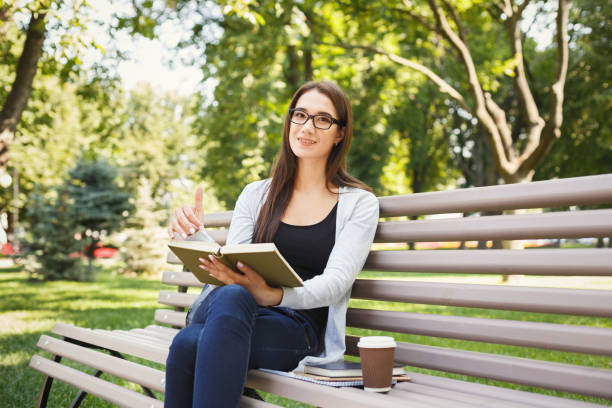 istock Young woman reading book in park copy space 906758920