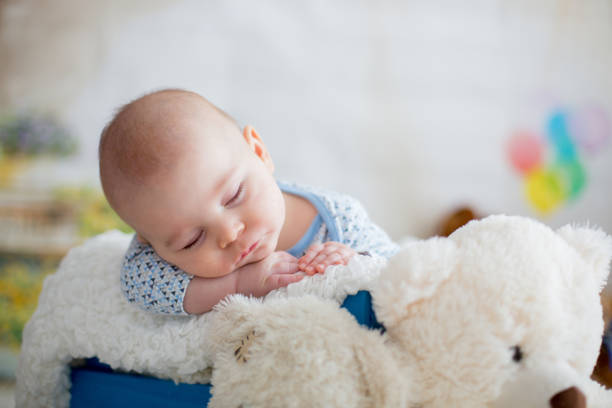 istock Little baby boy with knitted hat, sleeping with cute teddy bear 906765586