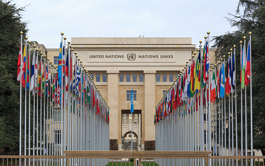 Geneva, Switzerland - Aug 16, 2020: Row of flags at entrance of United Nations Offices or Palais des Nations in Ariana Park, on shore of Lake Geneva. Since 1966 is main European headquarters of UN.