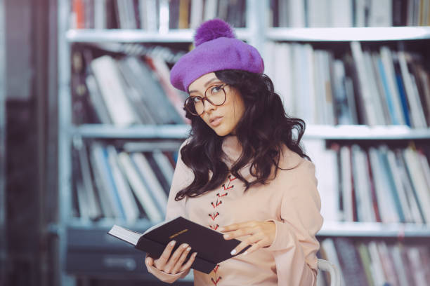 istock Asian student holding book in the library 906768534