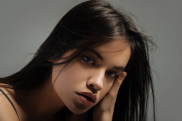 istock Stony-faced dark-haired woman touching her face 906771922