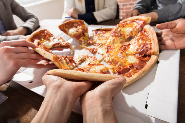 istock Group Of Businesspeople Eating Pizza 906777402
