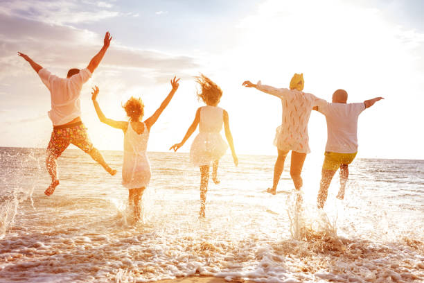 grupo de cinco pueblos, correr y saltar al mar al atardecer - family beach vacations travel fotografías e imágenes de stock