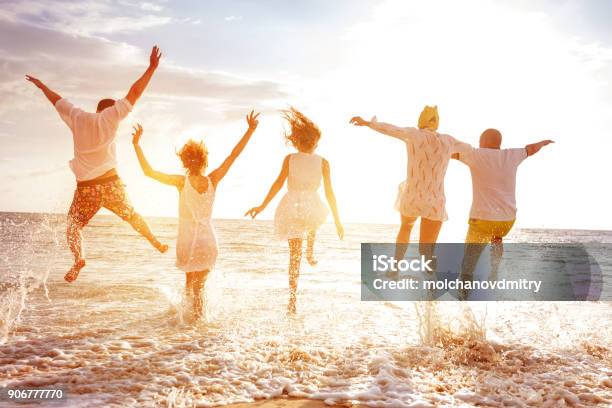 Group Of Five Peoples Run And Jump To Sunset Sea Stock Photo - Download Image Now - Family, Beach, Summer