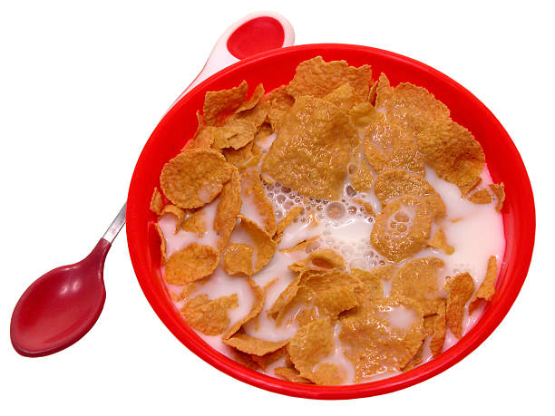 Food: Toddler Bowl of Cerial Little red bowl of generic corn flake cerial with a red and white spoon beside.  Shot on white. Not an isolaion. cerial stock pictures, royalty-free photos & images