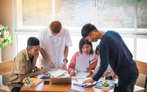 istock Asian College groups of students using laptop, tablet, studying together with notebooks documents paper for report near windows in classroom. Happy young study for school assignment, Education Concept 906782948