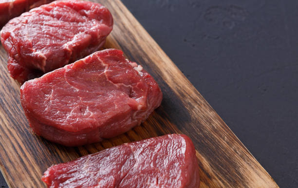 istock Raw beef filet mignon steaks on wooden board at gray background 906783292