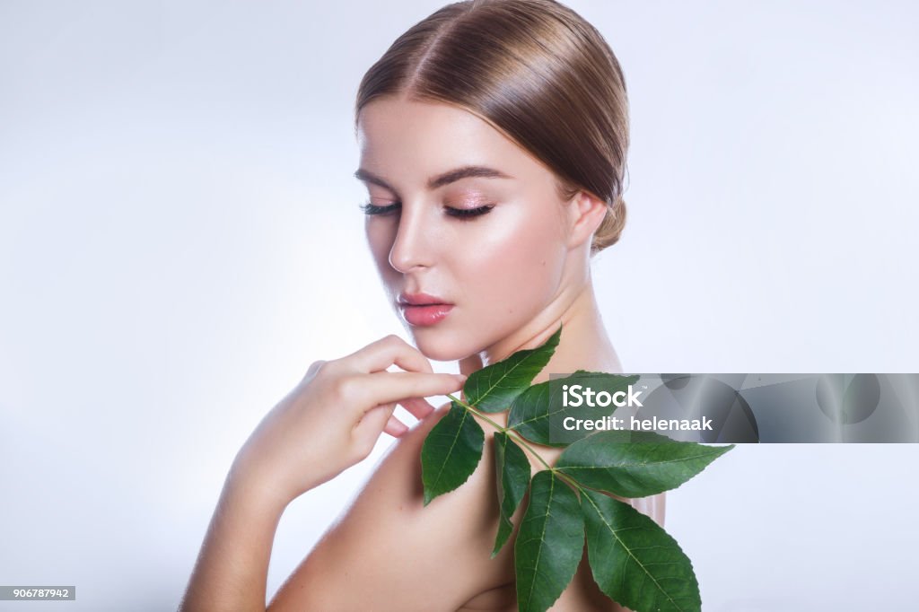 organic cosmetic . Beautiful woman face portrait with green leaf , concept for skin care or organic cosmetics . Beautiful woman face portrait with green leaf , concept for skin care or organic cosmetics Beauty Stock Photo