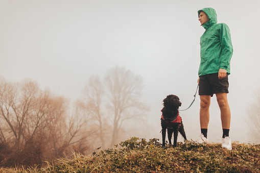 Photo of active young man and his dog in a morning walk