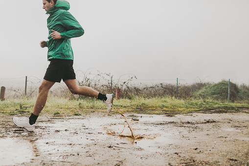 Photo of active man running in a cold, foggy, rainy morning
