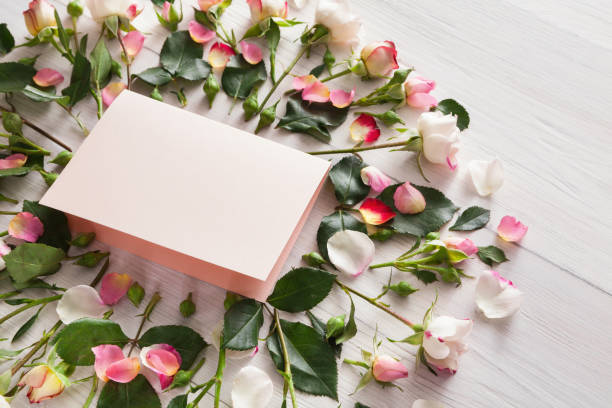 istock Handmade paper card in pink natural roses frame on white rustic wood 906794202