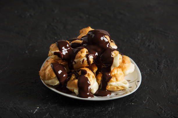 вкусный profiterole на темном фоне - профитроль стоковые фото и изображения