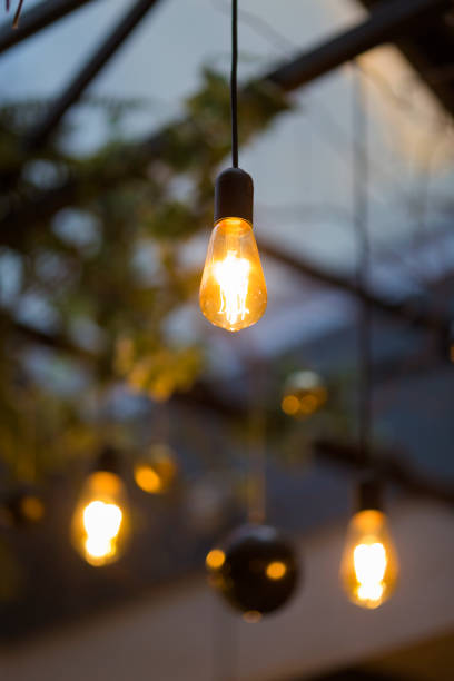 istock Old style electric bulbs and Christmas tree balls hanged on blurred background with focus on the foreground bulb 906797464