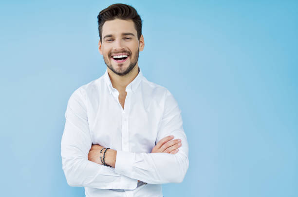 Handsome man Sexy smiling handsome man with crossed arms light blue photos stock pictures, royalty-free photos & images