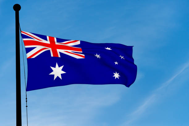 istock Australian Flag waving over blue sky (3D rendering) 906808120
