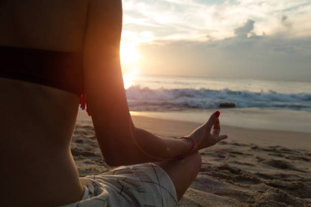 istock Young woman practicing yoga on the tropical beach. 906818924