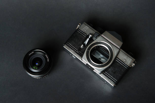 istock Old film camera and manual lens, black background. 906829612