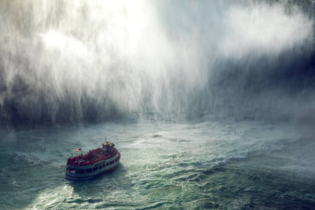 Tourists on a boat experience the sheer force of Niagara Falls as water cascades dramatically around them.