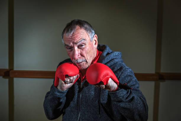 Senior man at the gym in boxing gloves Senior man at the gym in boxing gloves old man boxing stock pictures, royalty-free photos & images
