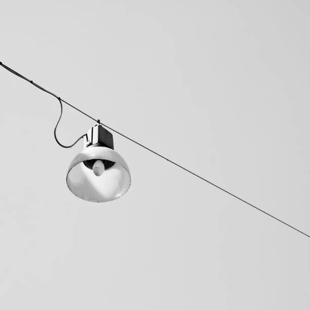 istock Single streetlight hanging from a metal cable on black and white background 906854784