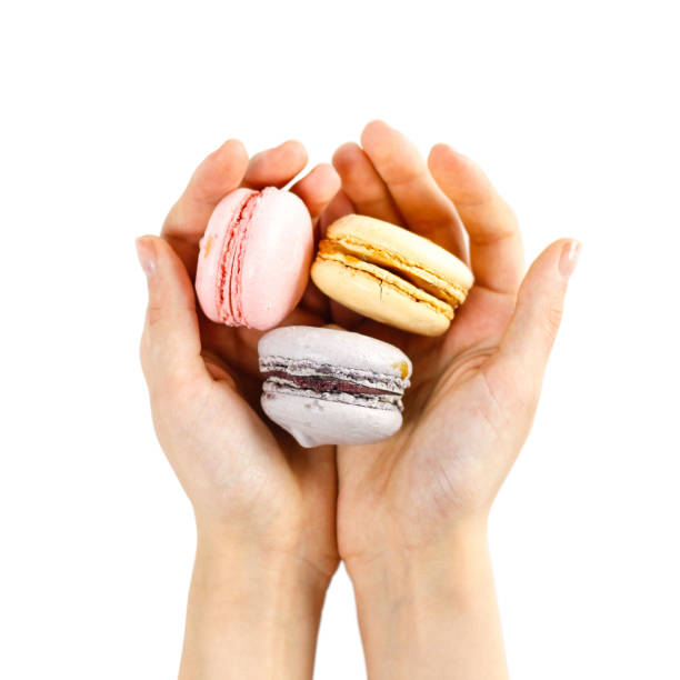 istock Hand holds colorful macaroons on a white background. Closeup 906858028