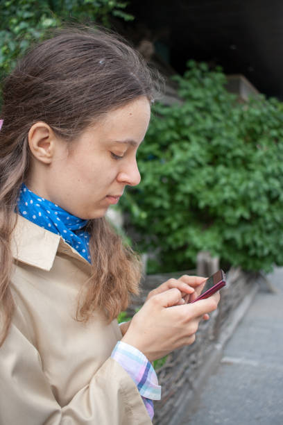 istock Young girl is looking in a smartphone that holds in his hands. 906858568