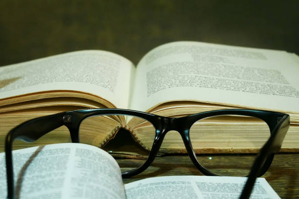 istock Open Bible with Glasses on the Old Table. 906869992