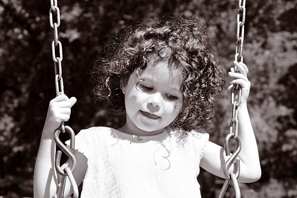 Two little girls having fun in nature on a swinging bench