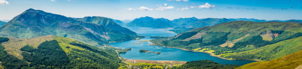 Scotland aerial panorama across Glencoe Loch Leven Highlands glens mountains Panoramic vista across the green summer mountains of the Highlands from the tranquility of Glencoe village to the blue shores of Loch Leven and Loch Linnhe, Lochaber, Scotland. fort william stock pictures, royalty-free photos & images