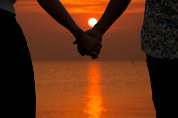 istock Couple holding hands and blurry beautiful sunset in background 906892644