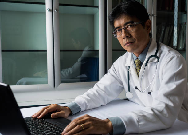 istock Confident asian doctor sitting at desk working on laptop 906894812