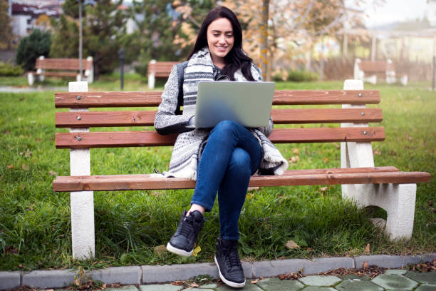 istock Woman using a laptop outdoors 906901180