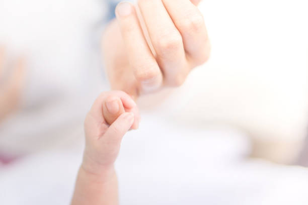 istock new born little hand holding mum finger in soft tone background 906902038