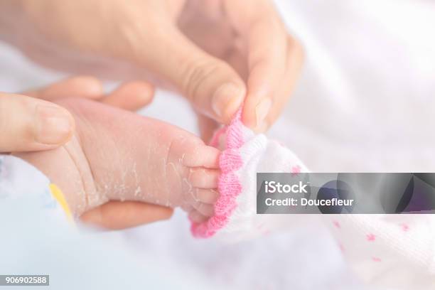 Mother Hand Wearing Socks For Newborn Baby Feet In Winter Stock Photo - Download Image Now