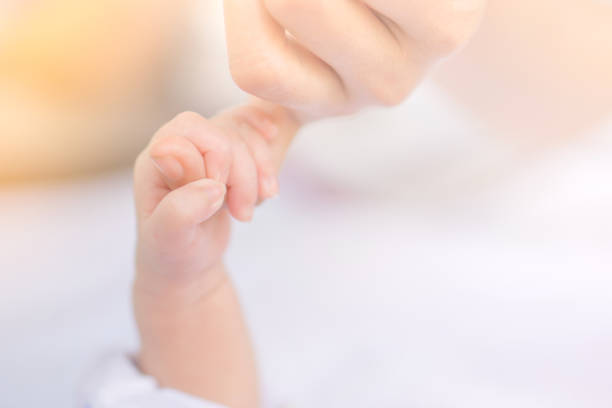 родился маленькая рука, держащая маминый палец в мягком фоне тон - new childbirth new life love стоковые фото и изображения