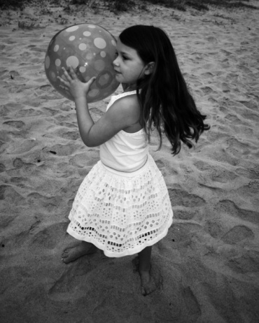 A girl at the beach with a ball 