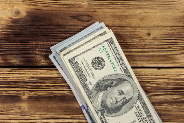 istock Stack of one hundred dollars bills on wooden desk 906953758