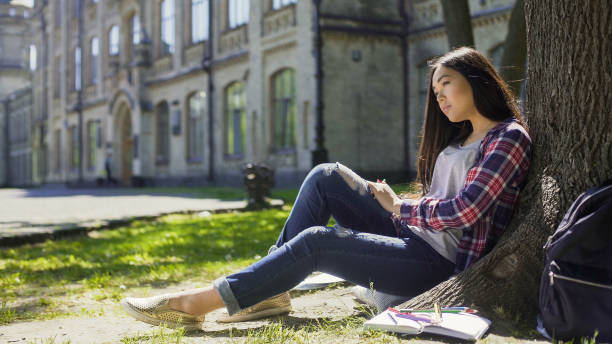 istock Multinational young woman sitting calmly under tree looking ahead, observation 906963512